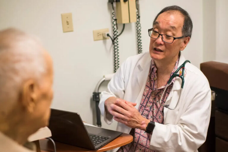 Doctor sitting at small desk talking with patient