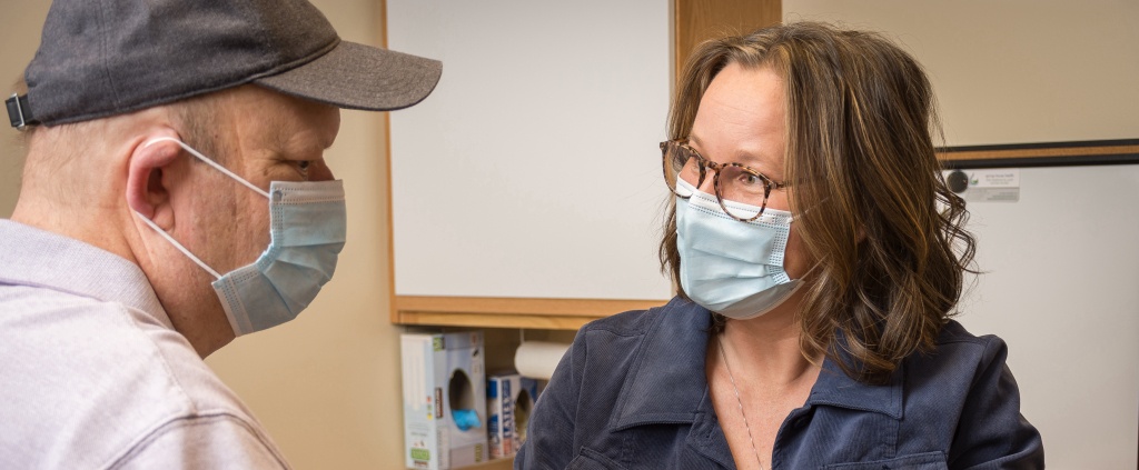 Doctor wearing mask conversing with patient