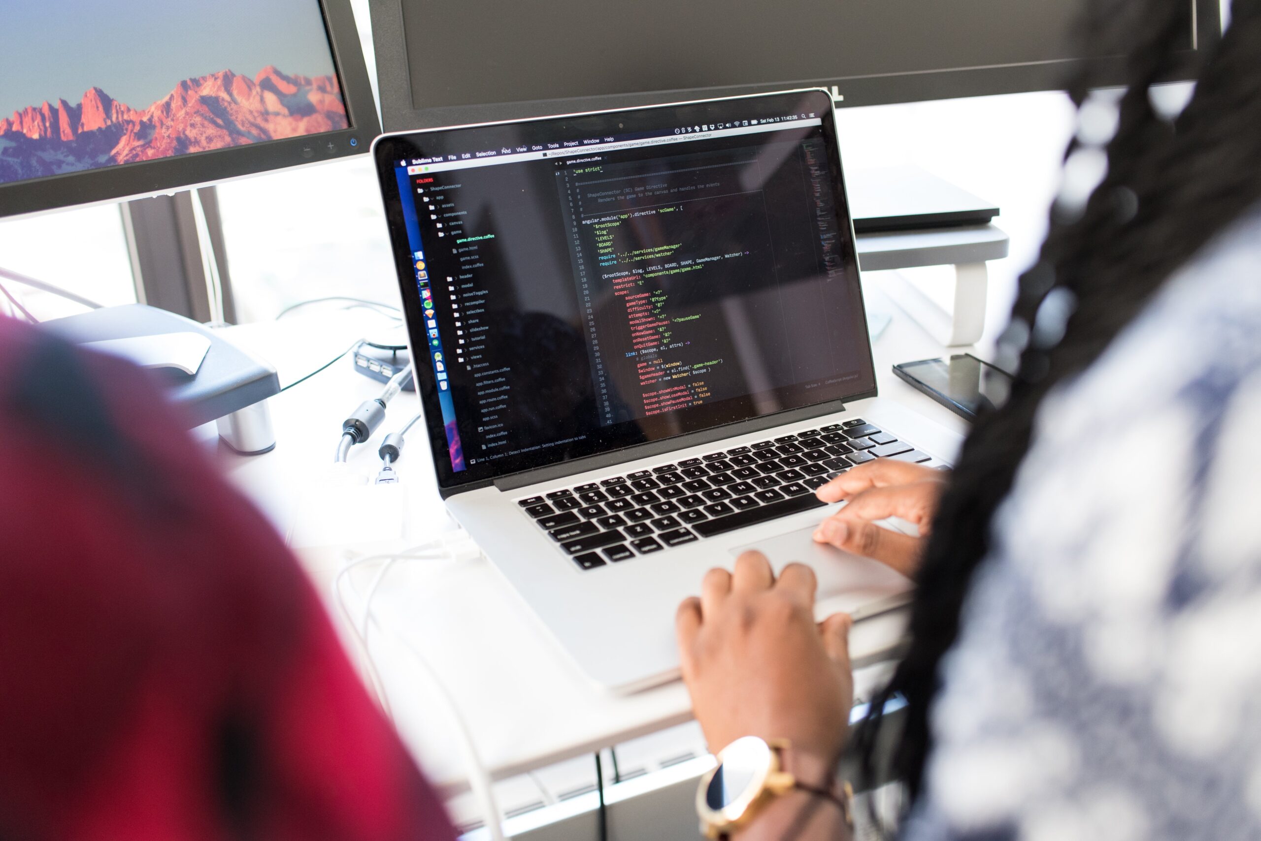 Developer sitting at desk coding on laptop