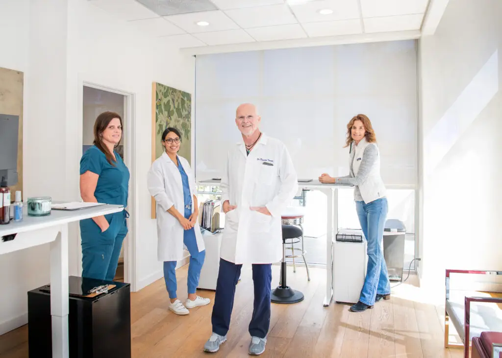 Doctors standing around desk smiling