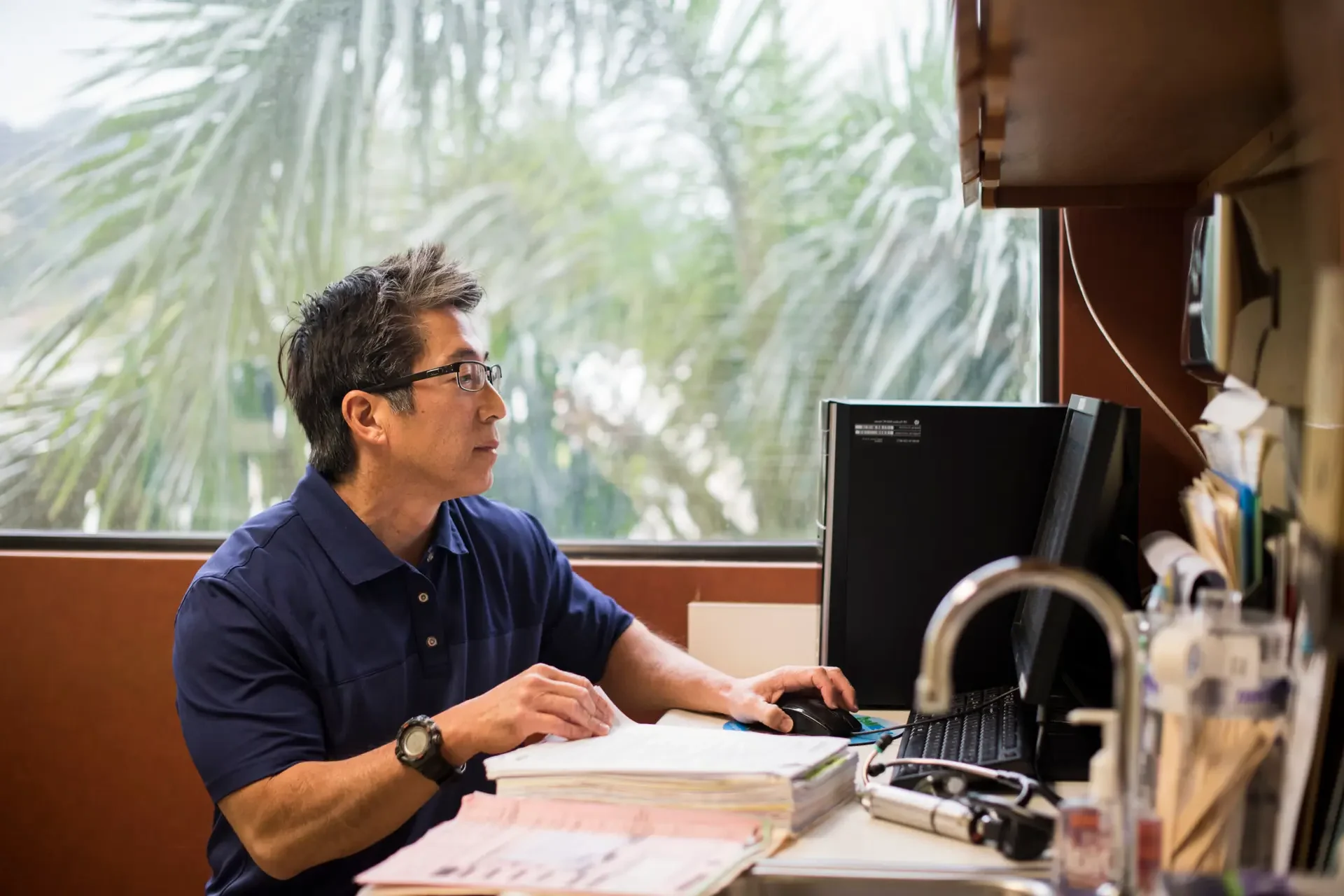 Doctor sitting in exam room looking at computer screen