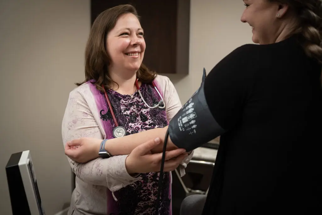 Doctor smiling while checking patient's blood pressure
